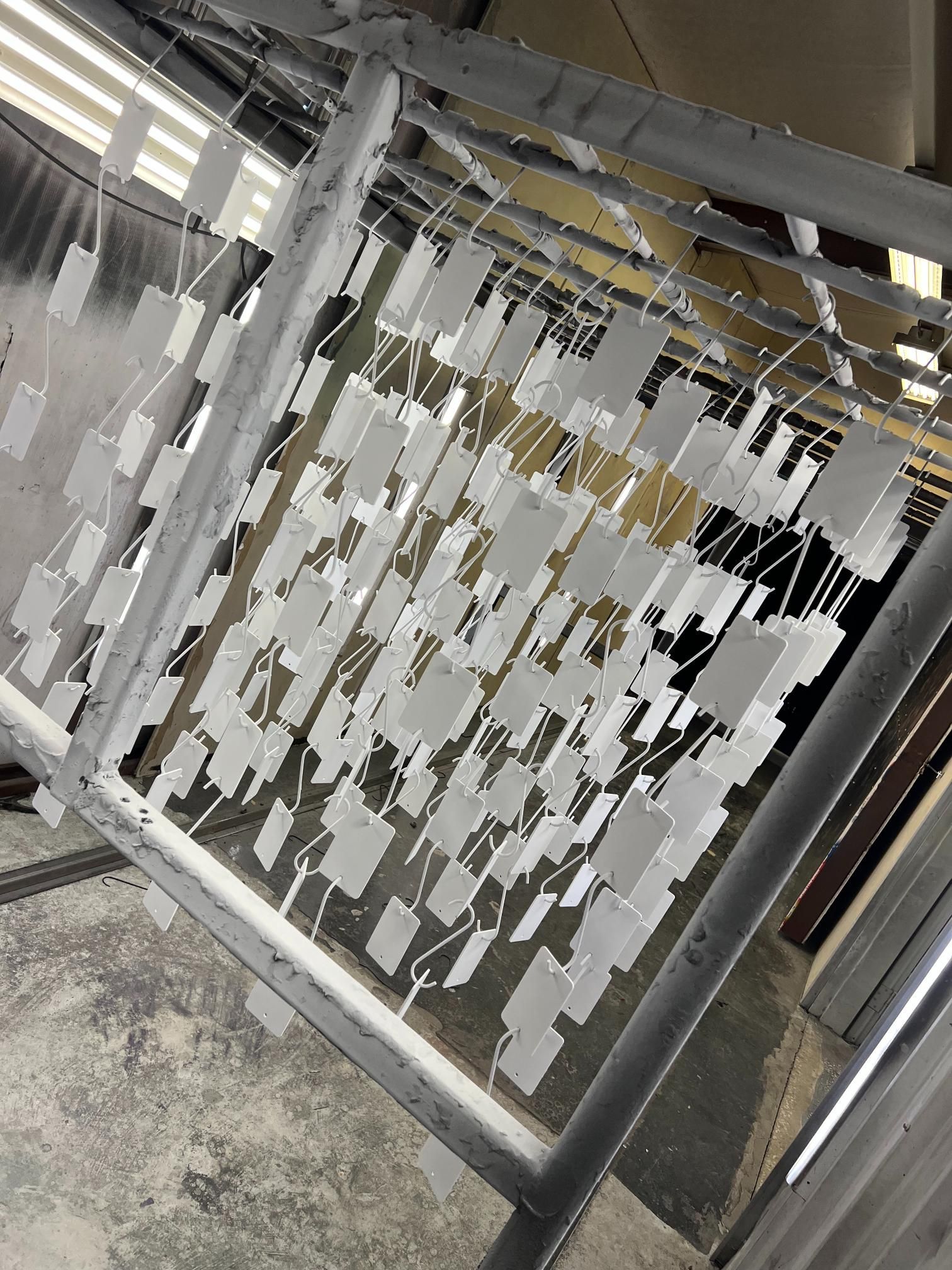 Red car wheel rims hanging in a spray painting booth.