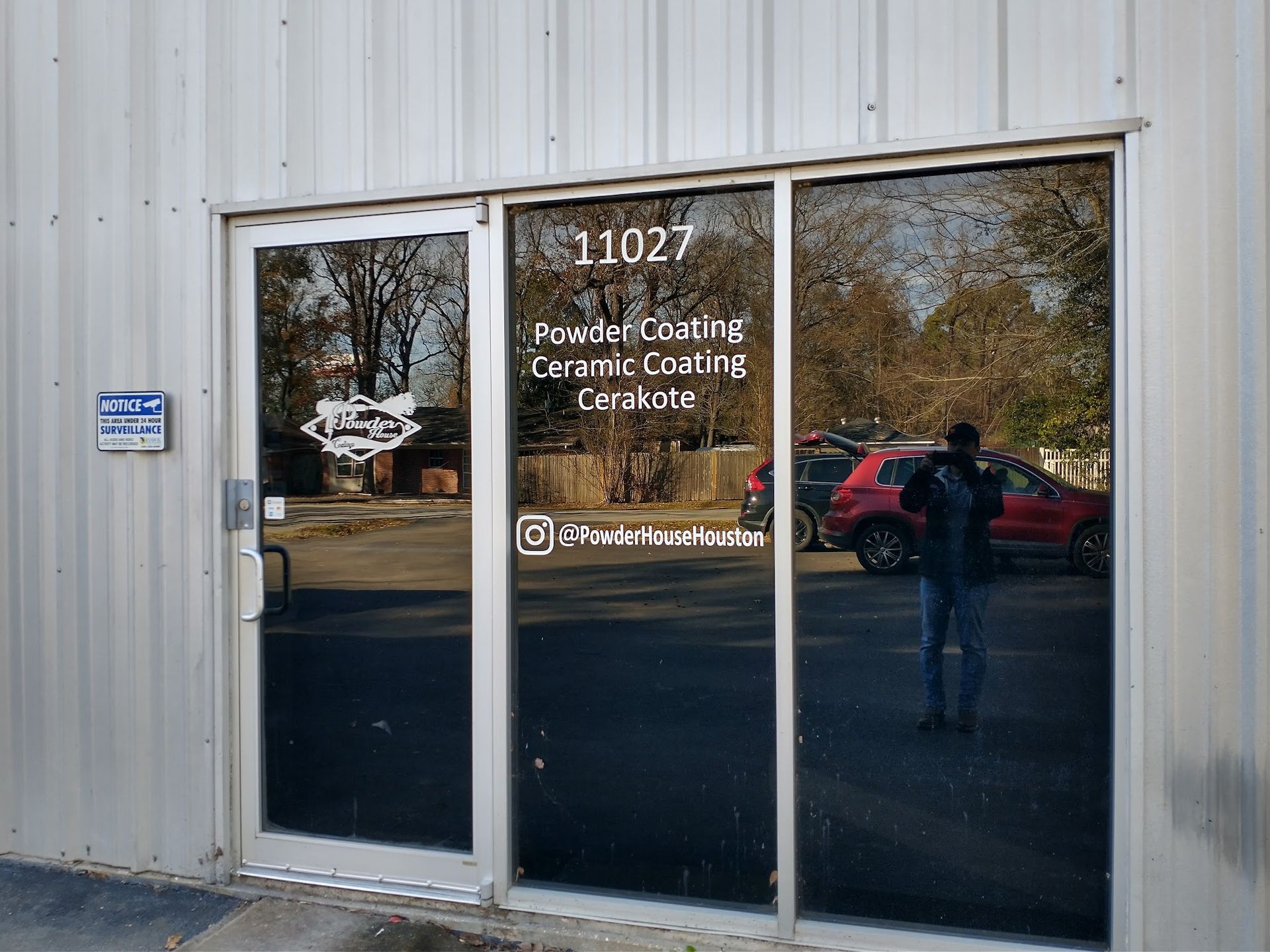 Exterior of a building with glass doors, displaying business information and address 11027. A person stands near the doors.