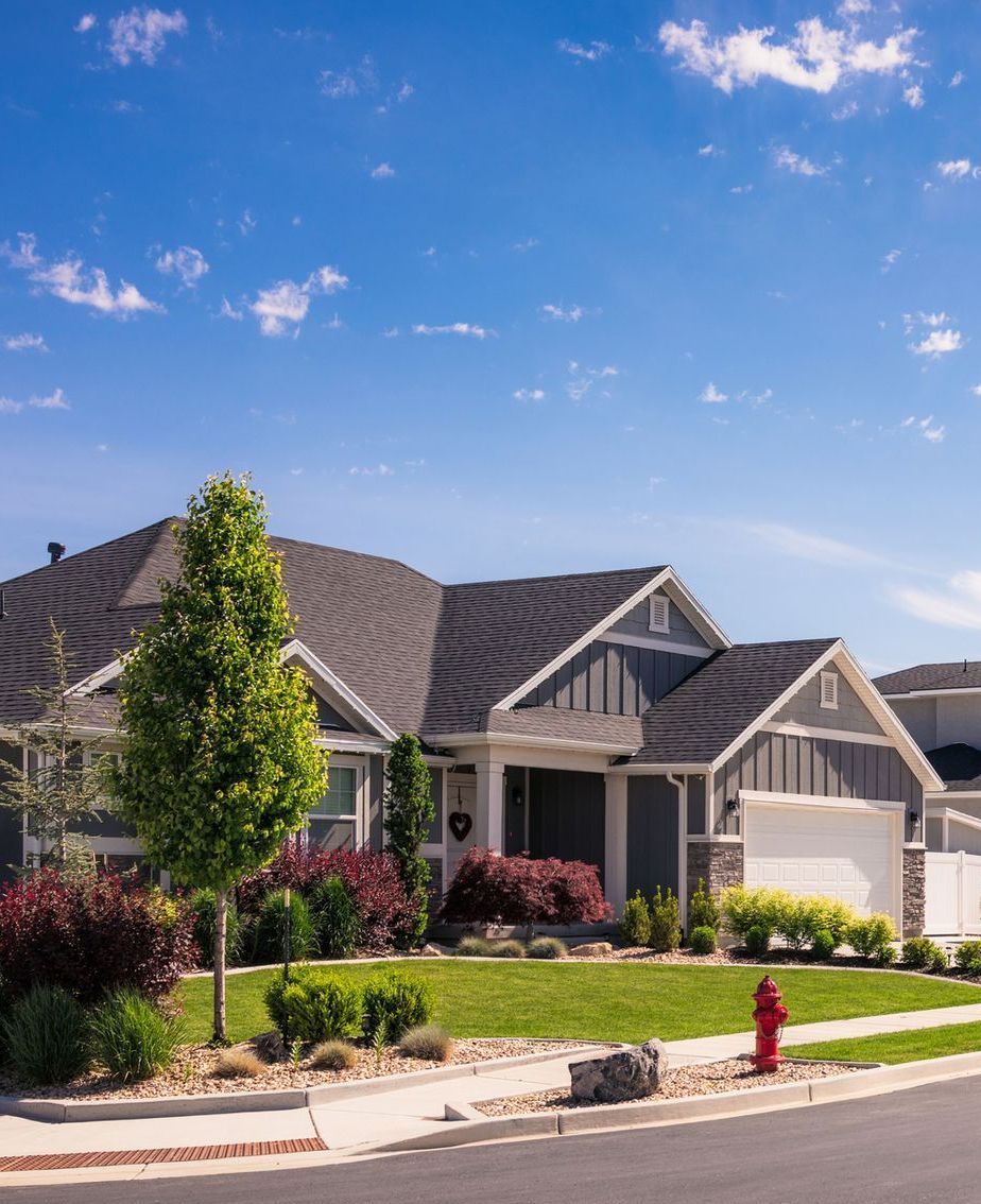 A house with a fire hydrant in front of it on a sunny day .