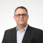 A man in a suit and glasses is smiling for the camera.