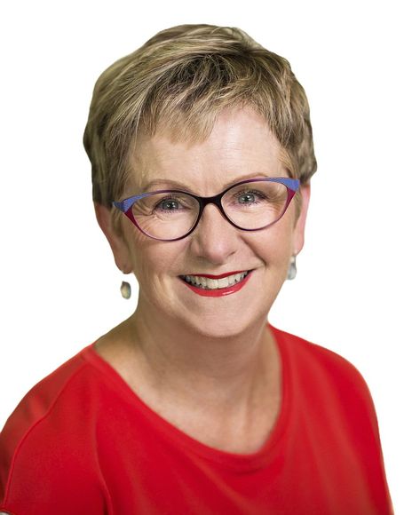 A woman wearing glasses and a red shirt is smiling for the camera.