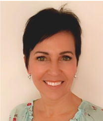 A woman with short hair and earrings smiles for the camera