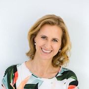 A woman wearing a floral shirt is smiling for the camera.