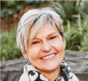 A woman with short hair is smiling for the camera while wearing a scarf.