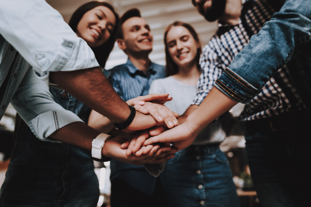 A group of people are putting their hands together in a huddle.