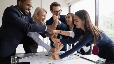 A group of people are putting their hands together in a huddle.