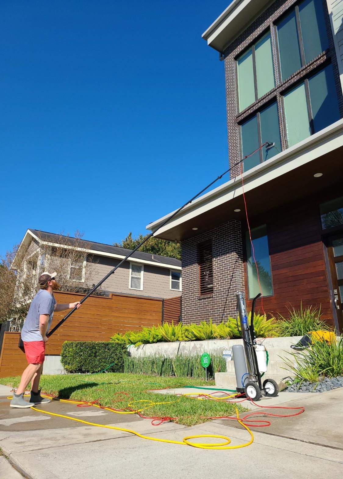 A man is cleaning the windows of a house with a high pressure washer.