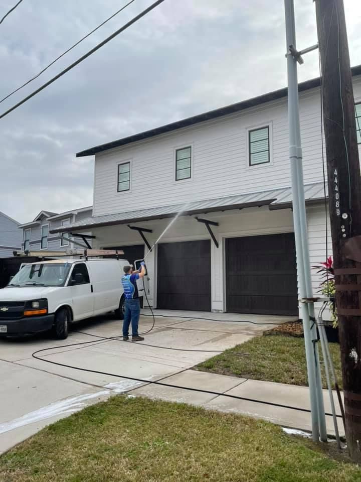 A man is washing the side of a house with a hose.
