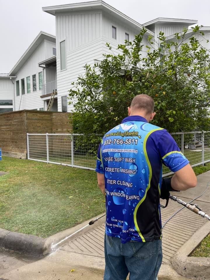 A man is cleaning a sidewalk with a pressure washer.