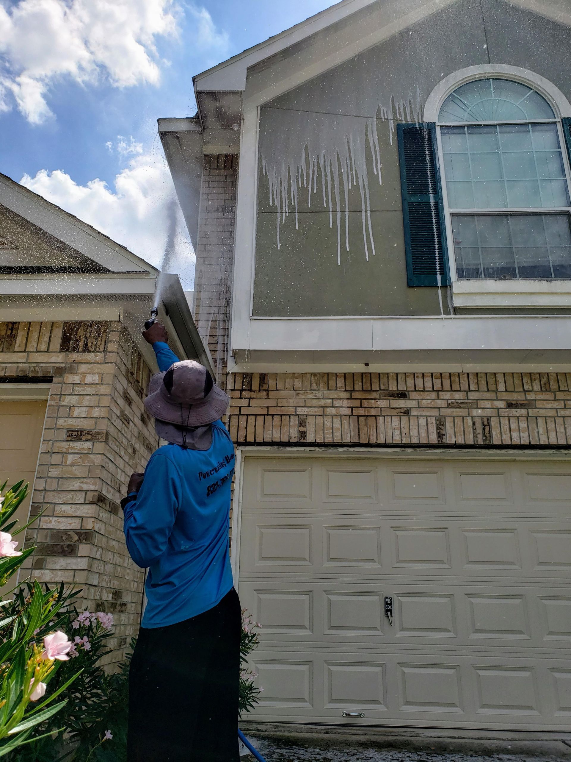 A man is cleaning a brick wall with a high pressure washer.