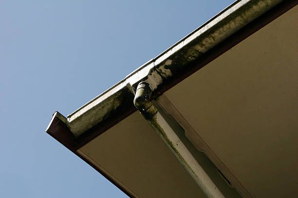 A close up of a gutter on a roof with a blue sky in the background