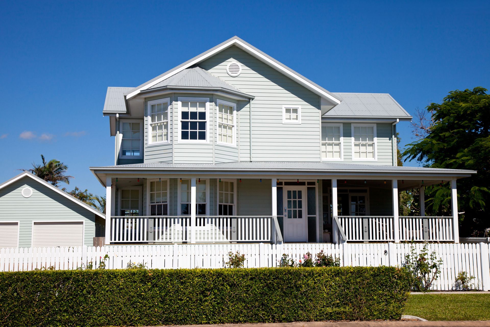 A large white house with a porch and a white fence