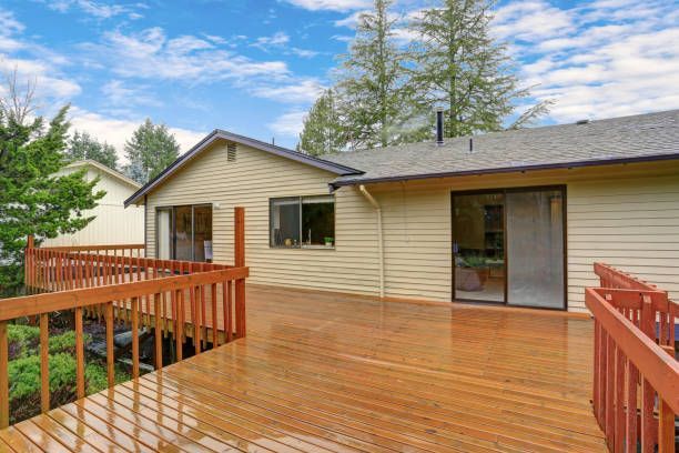 There is a large wooden deck in front of a house.