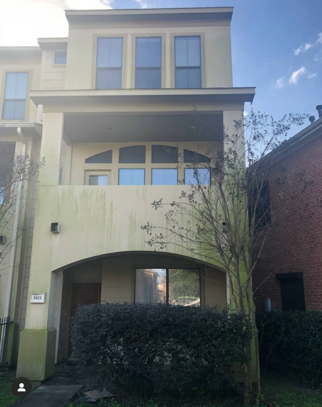 The back of a white house with a patio and chairs in the backyard.