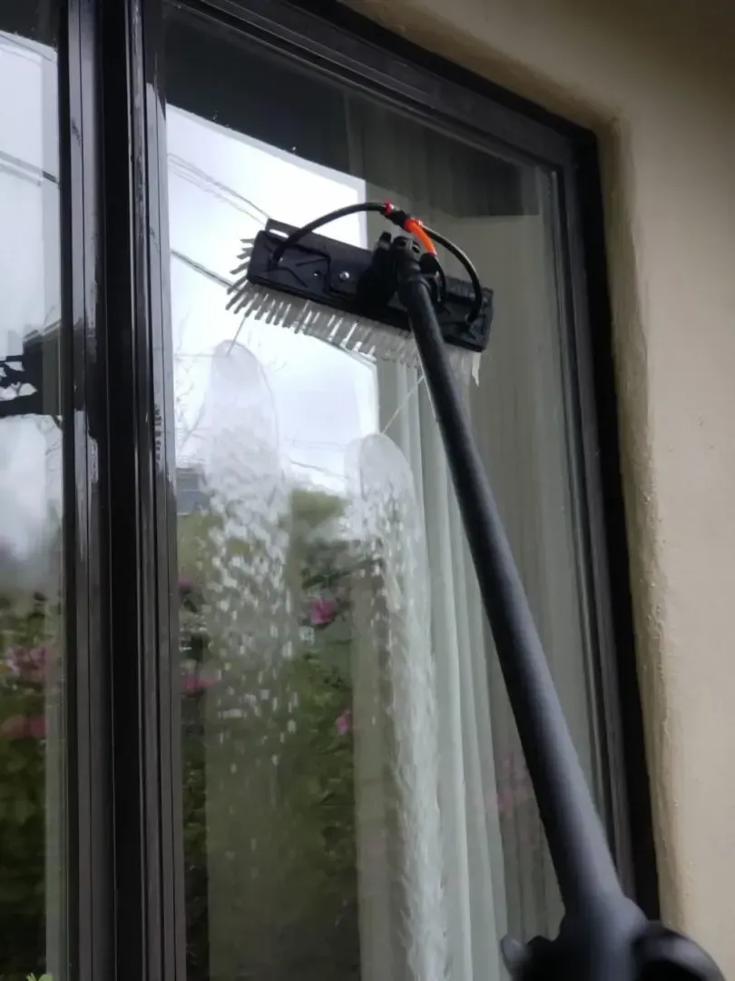 A person is cleaning a window with a broom.