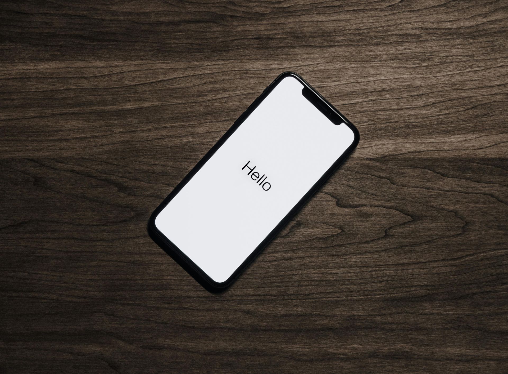 A cell phone is laying on a wooden table.