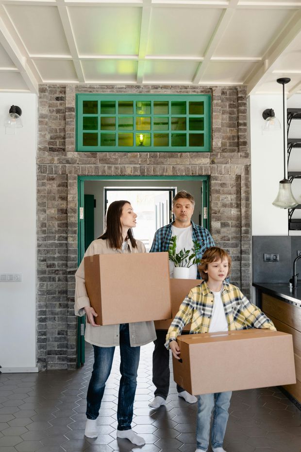 A family is carrying cardboard boxes into a new home.