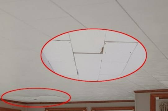 Damaged ceiling with a large section missing and smaller area peeling, likely water damage, indoors.
