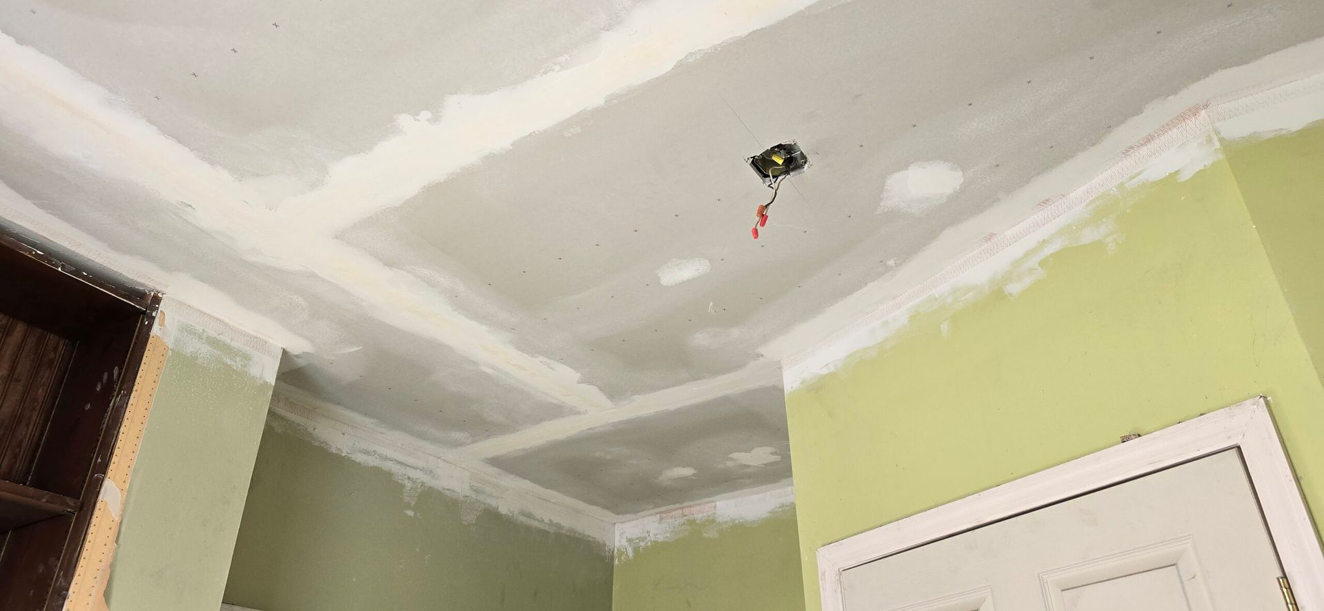 Ceiling construction with light green walls and electrical wiring.