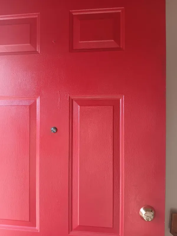 Red door with panels, doorknob, and peephole.