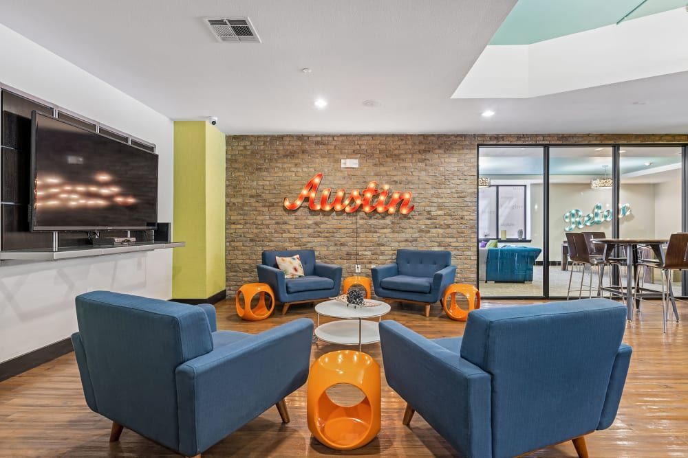 Apartment community social space with chairs, tables, and a television at Regents West at 24th in Austin, TX, near West Campus.