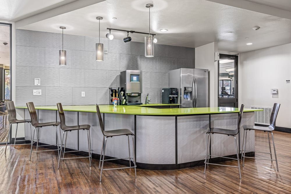 Community kitchen with a long counter and stools and a refrigerator at Regents West at 24th in Austin, TX, near West Campus.