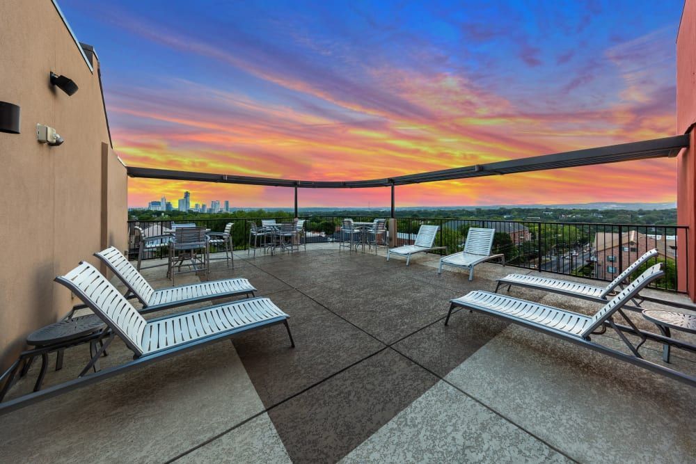 Rooftop terrace with lounge chairs and tables at sunset at Regents West at 24th in Austin, TX, near West Campus.