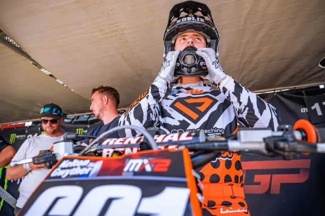 A man is standing next to a dirt bike with the number 60 on it