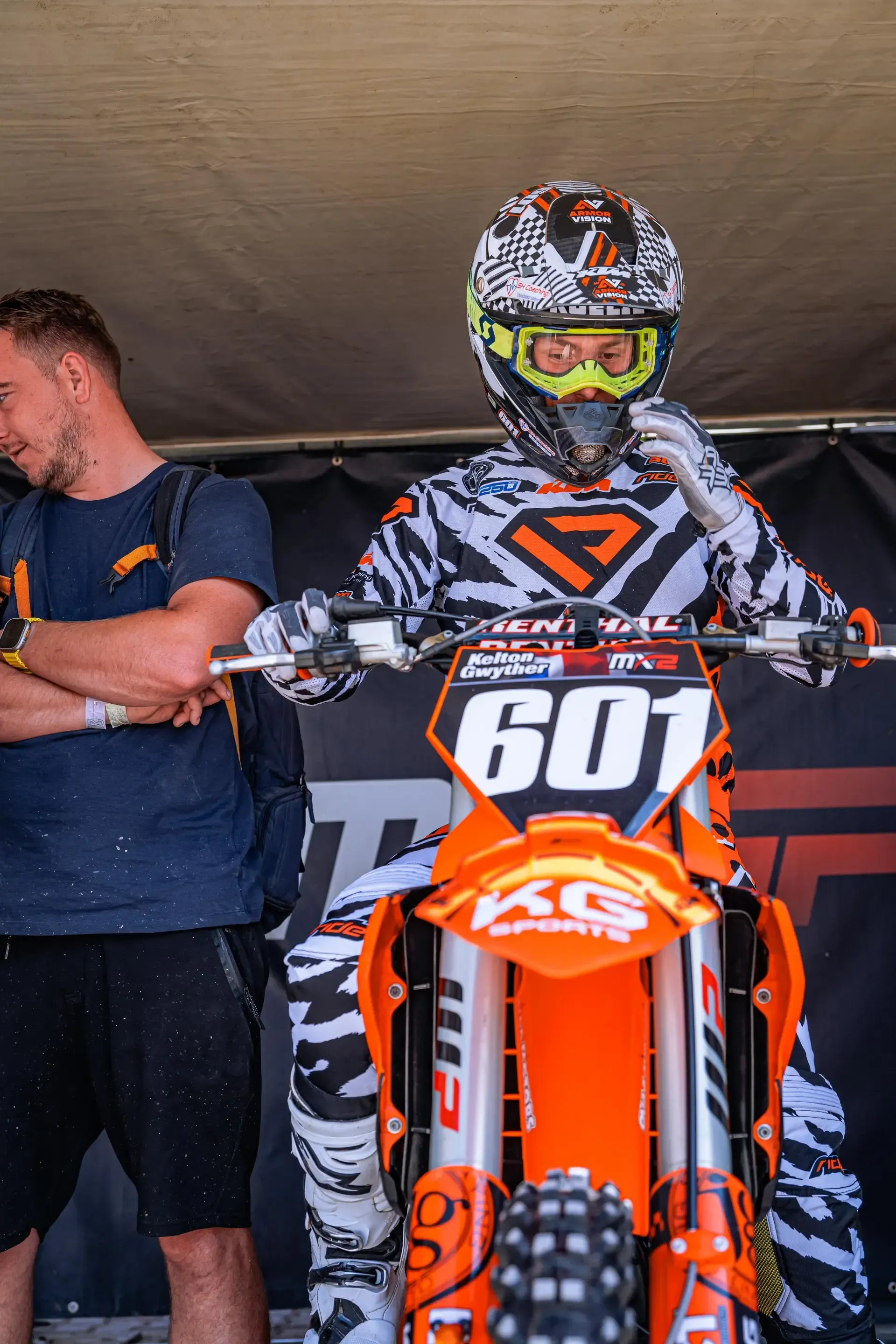 A man is standing next to a dirt bike with the number 601 on it.