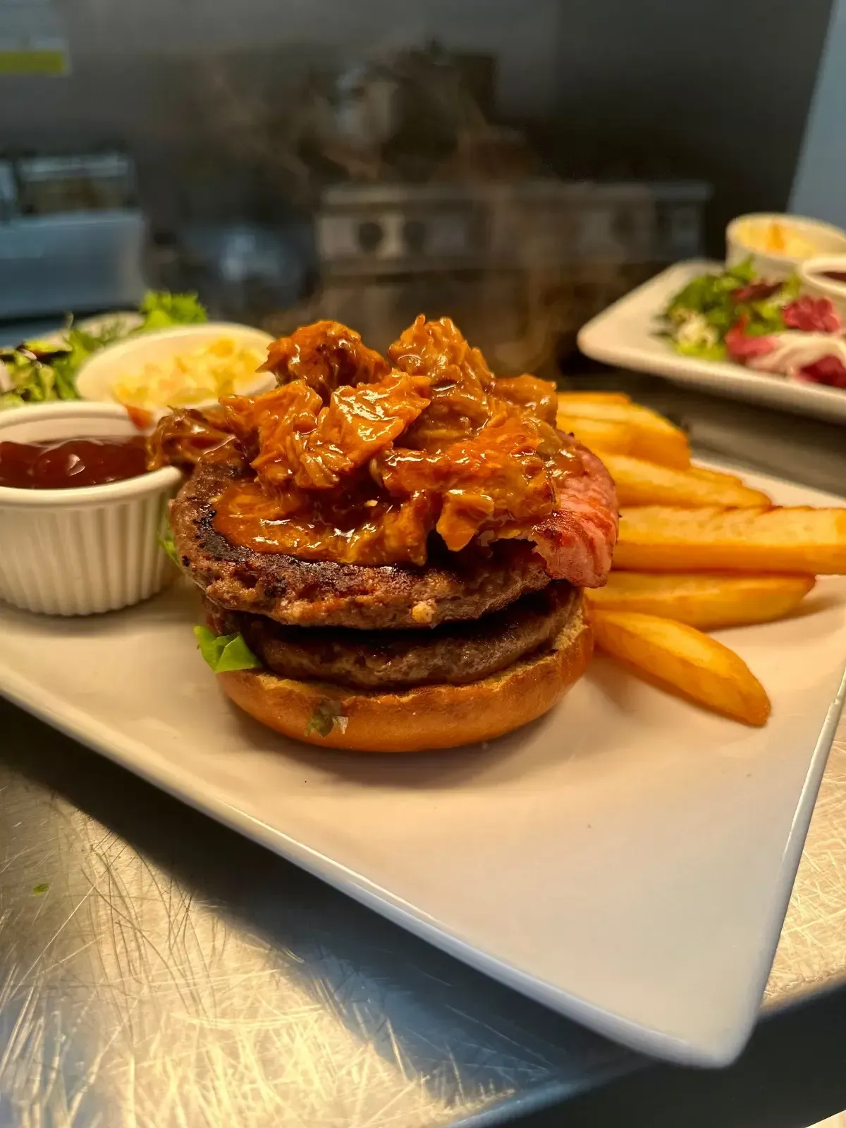 The Mackworth Arms, Laleston, Bridgend | Double-patty burger with fried toppings, fries, salad, and sauce on a white plate.