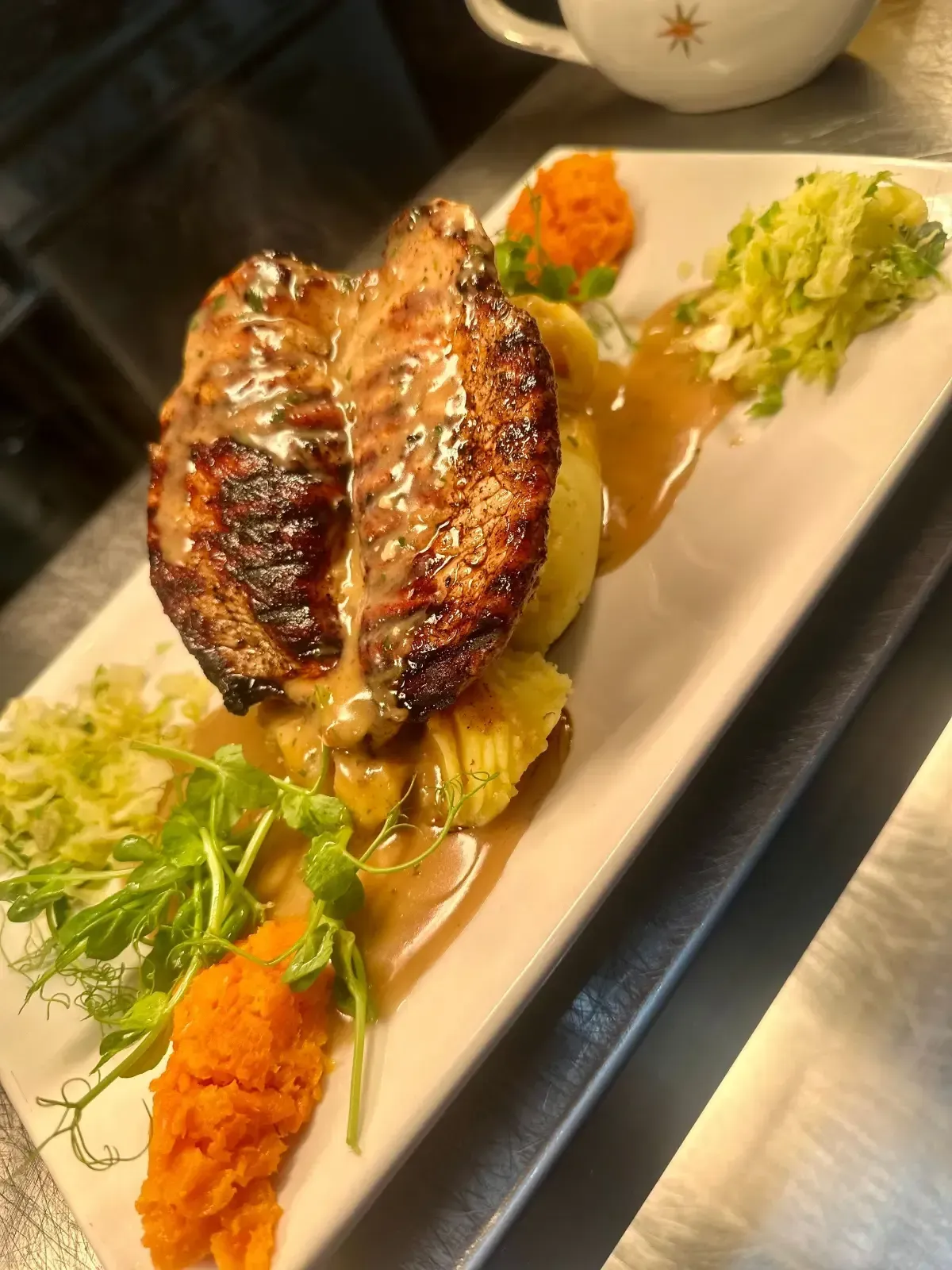 The Mackworth Arms, Laleston, Bridgend | Grilled pork loin with mashed potatoes, vegetables, and gravy on a white plate.