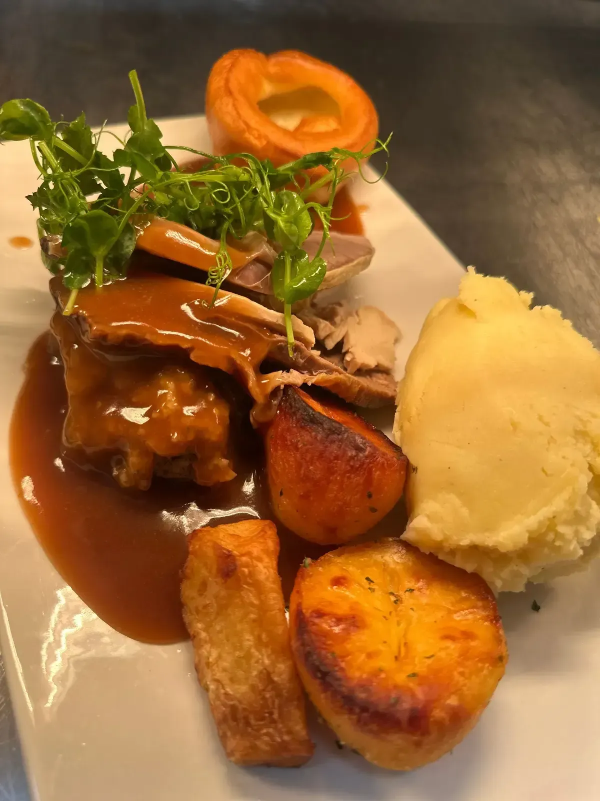 Mackworth Arms, Sunday Roast Menu | Roast dinner on white plate: meat, gravy, Yorkshire pudding, potatoes, and mash.