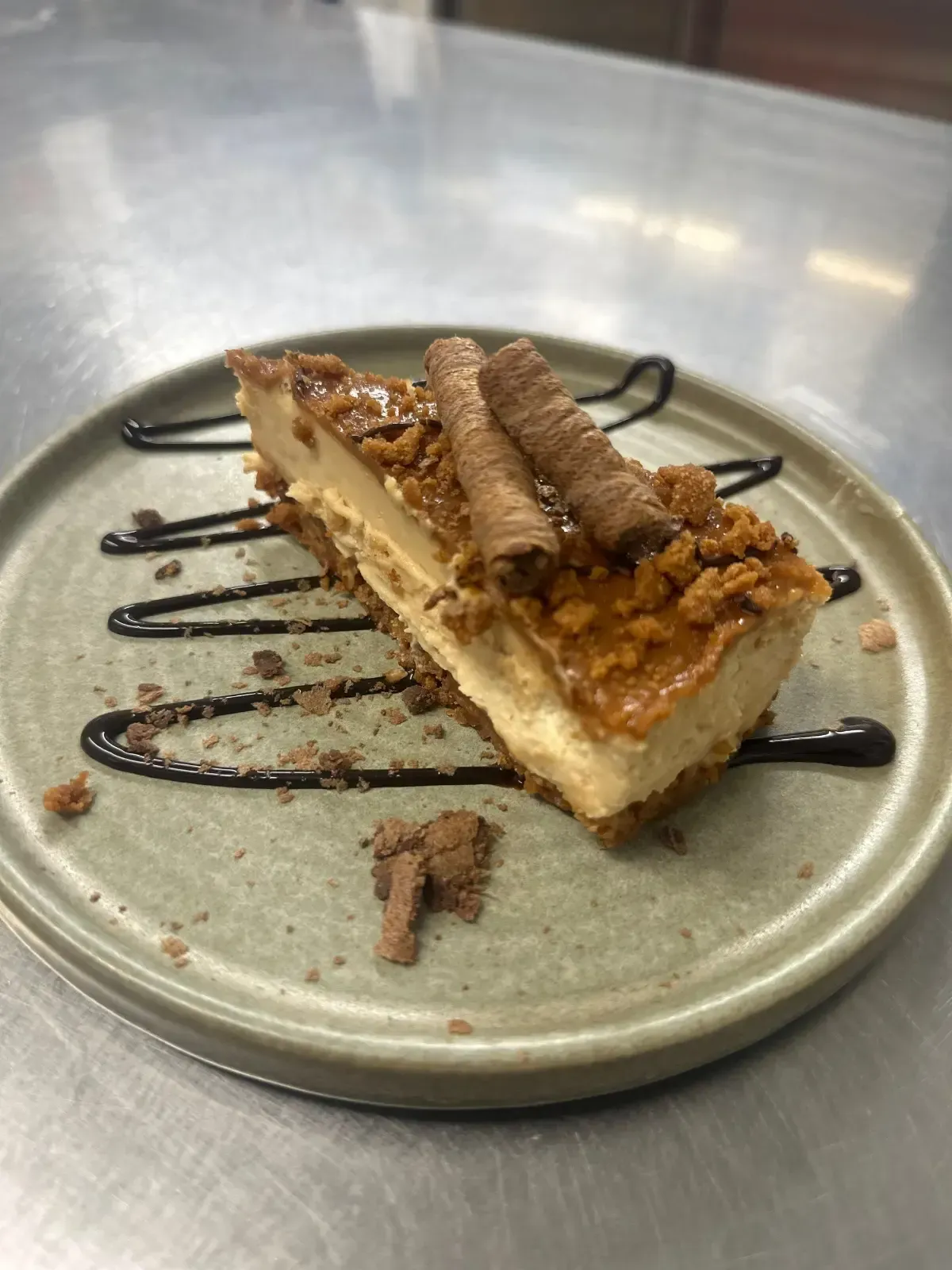 Mackworth Arms, Dessert Menu | Slice of cheesecake with caramel topping, chocolate drizzle on a green plate. 