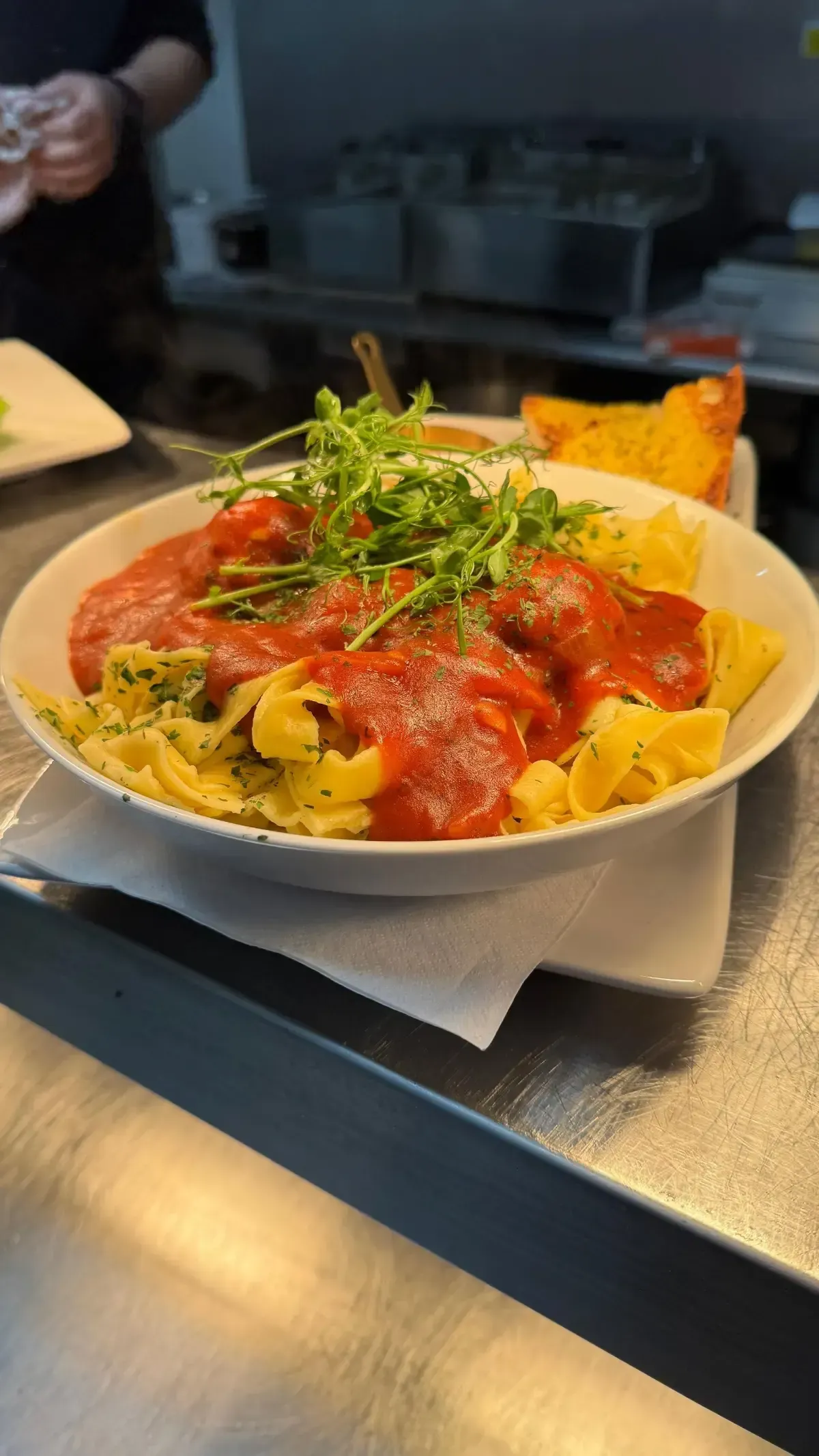 The Mackworth Arms, Laleston, Bridgend | Pasta with tomato sauce, topped with arugula, in a white bowl on a metal surface.