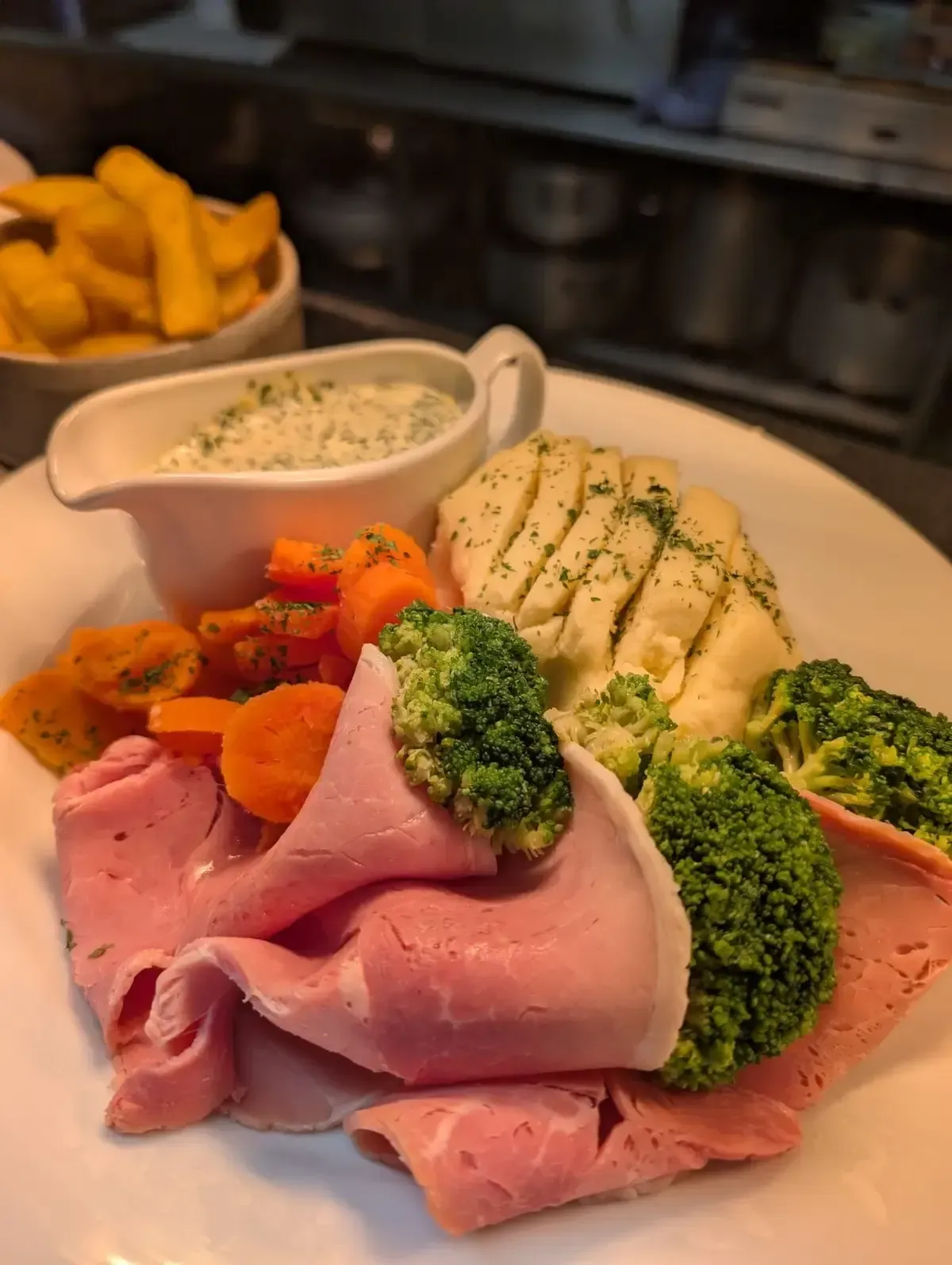 The Mackworth Arms, Laleston, Bridgend | Plate of ham, vegetables, mashed potato, and gravy boat, plus fries in a bowl.