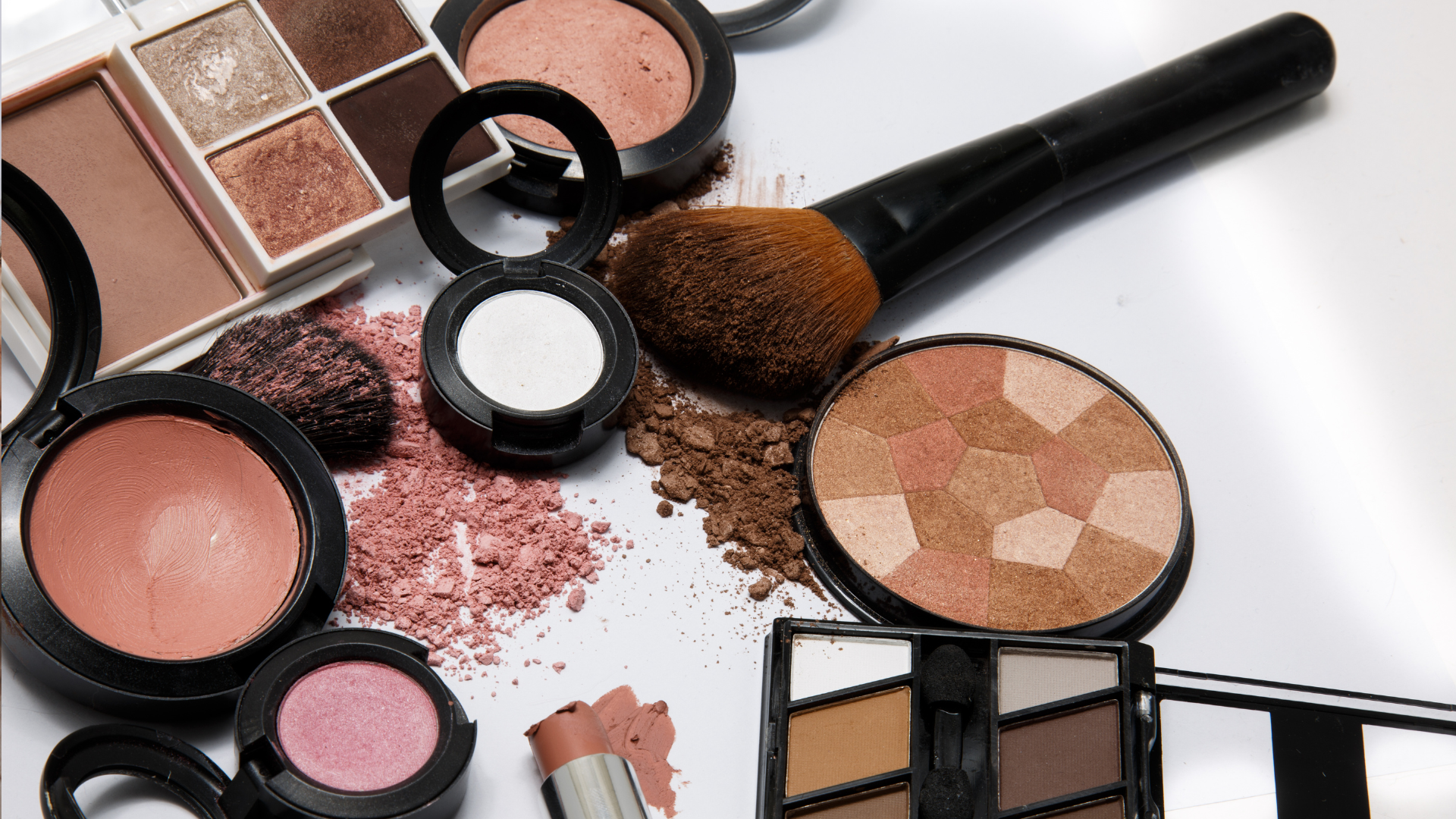 A brush is sitting on top of a pile of makeup.