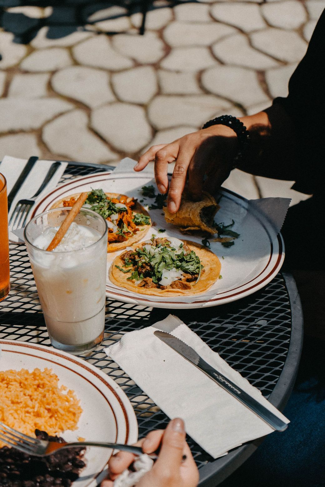 A person is sitting at a table with plates of food and a drink.