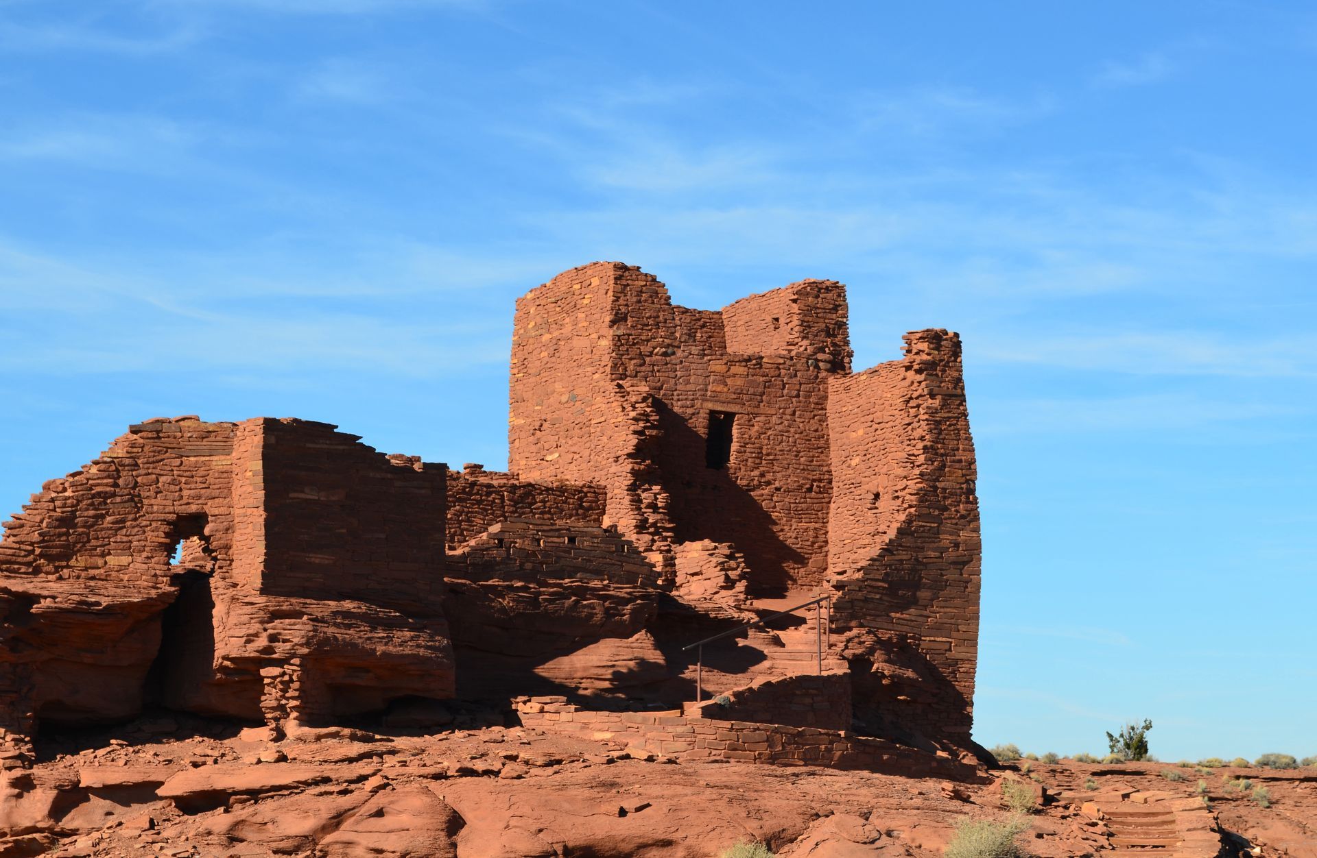Ruins of a red stone tower against a clear blue sky.