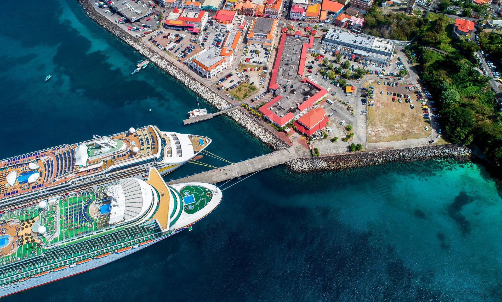 Cruise ships docked at a harbor, with colorful buildings and turquoise water.