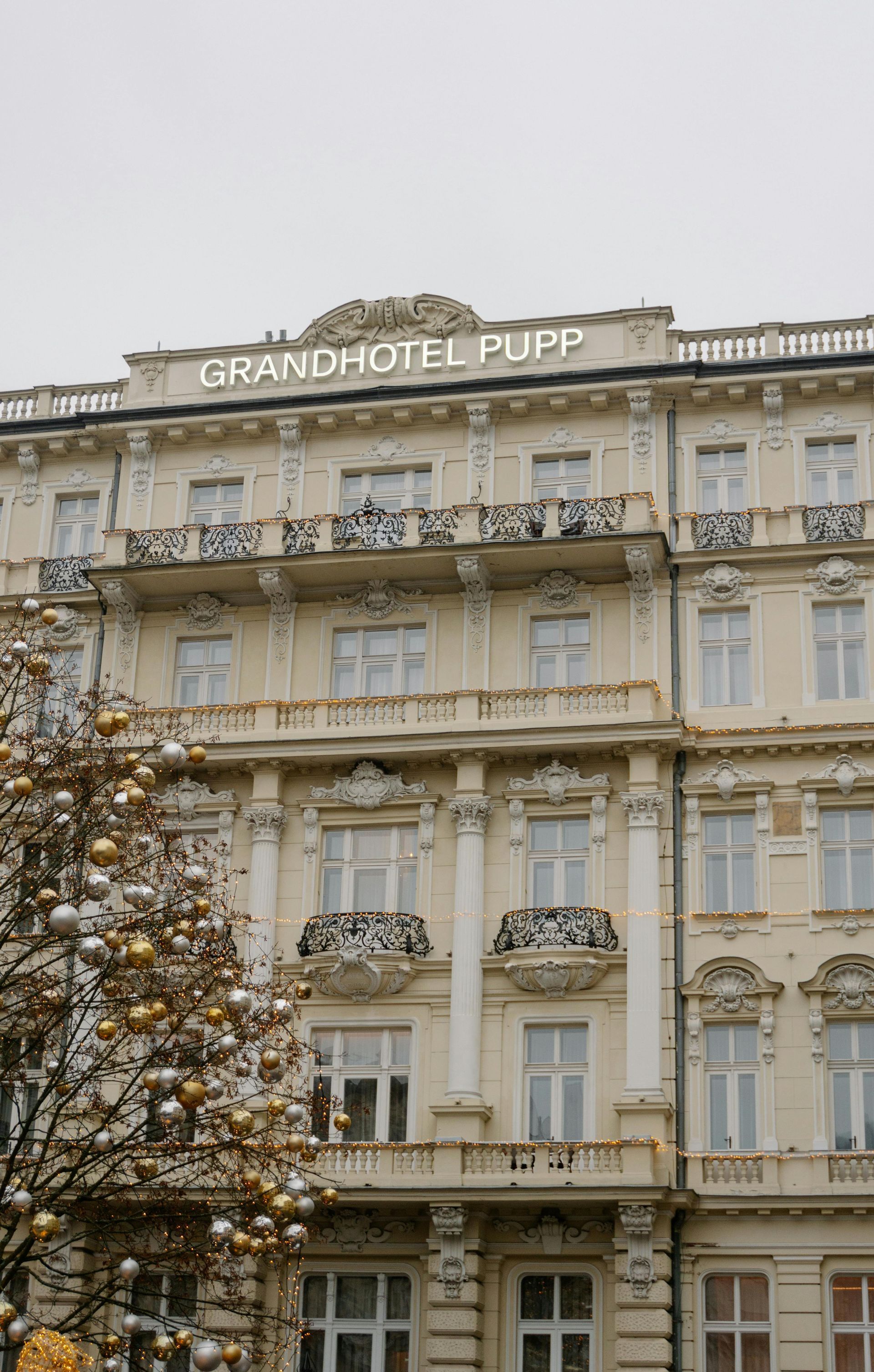 Grandhotel Pupp, beige building with white trim, ornate balconies, sign on top.