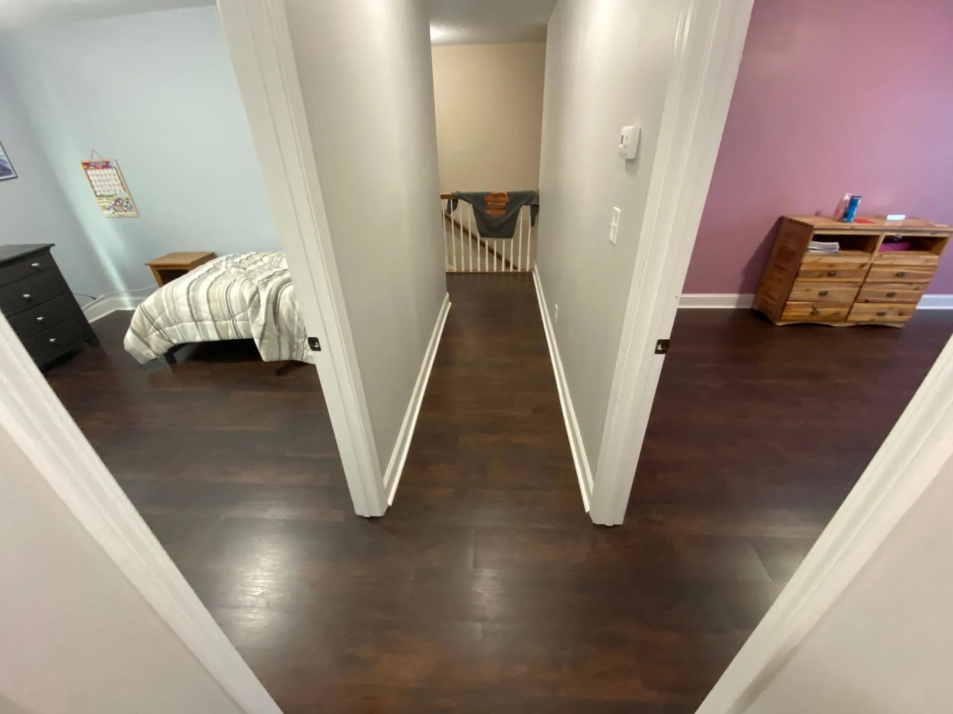 Hallway with dark wood floor, flanked by two doorways leading to bedrooms.