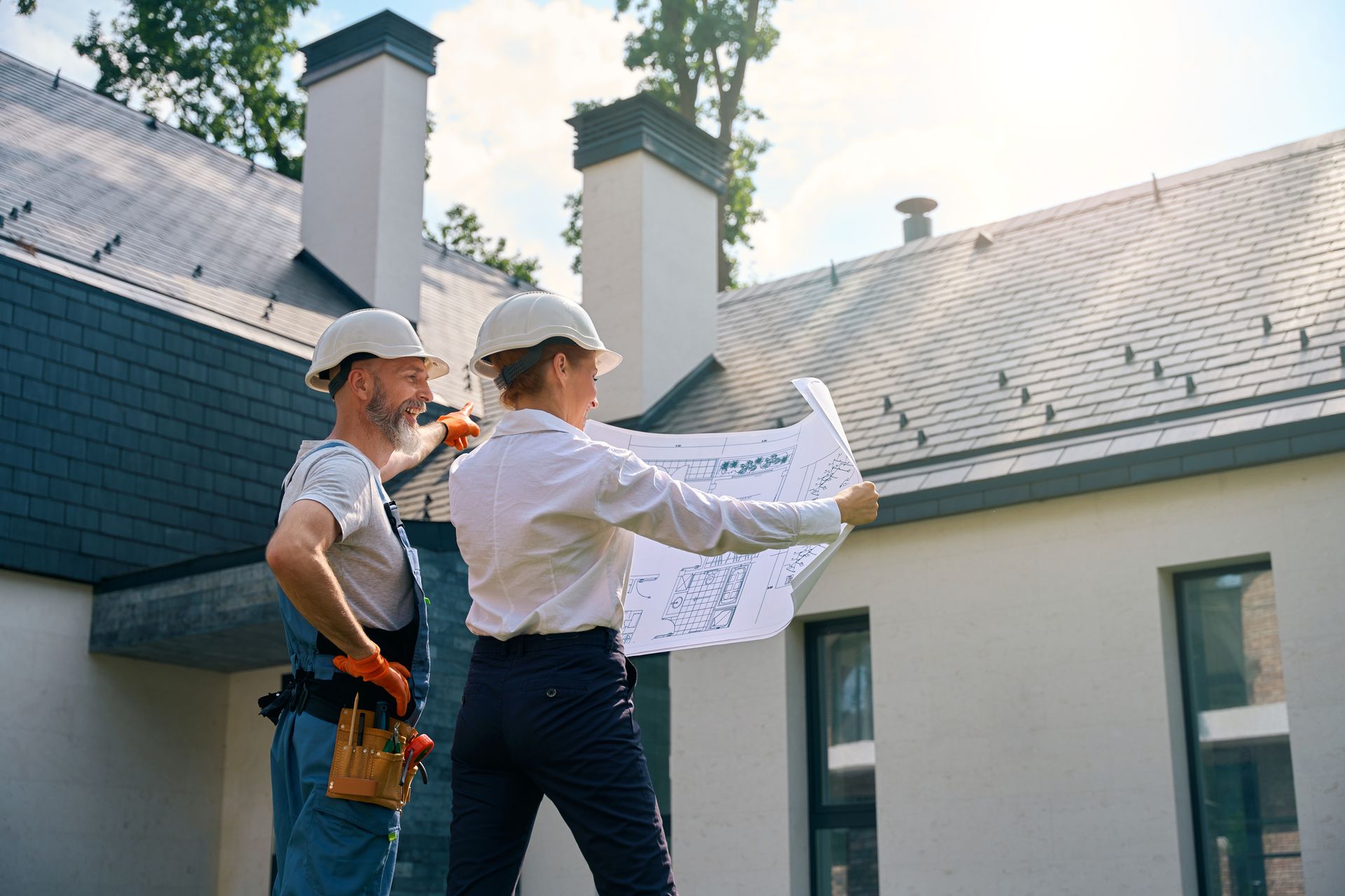 Builder and site supervisor using blueprints for roofing inspection.