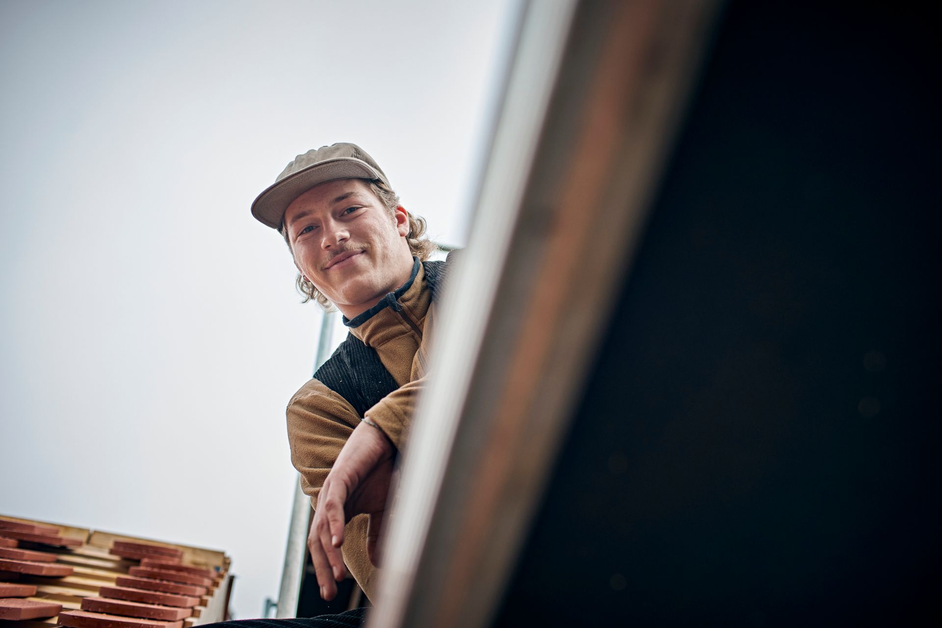 Portrait of a smiling carpenter on the roof of a house.