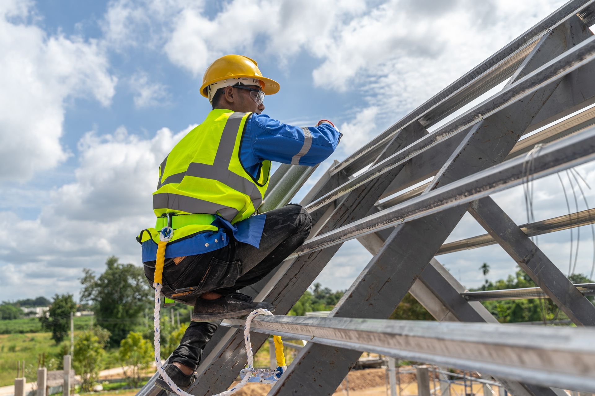 Image of a roofer worker in a helmet installing metal panels on an outdoor structure.