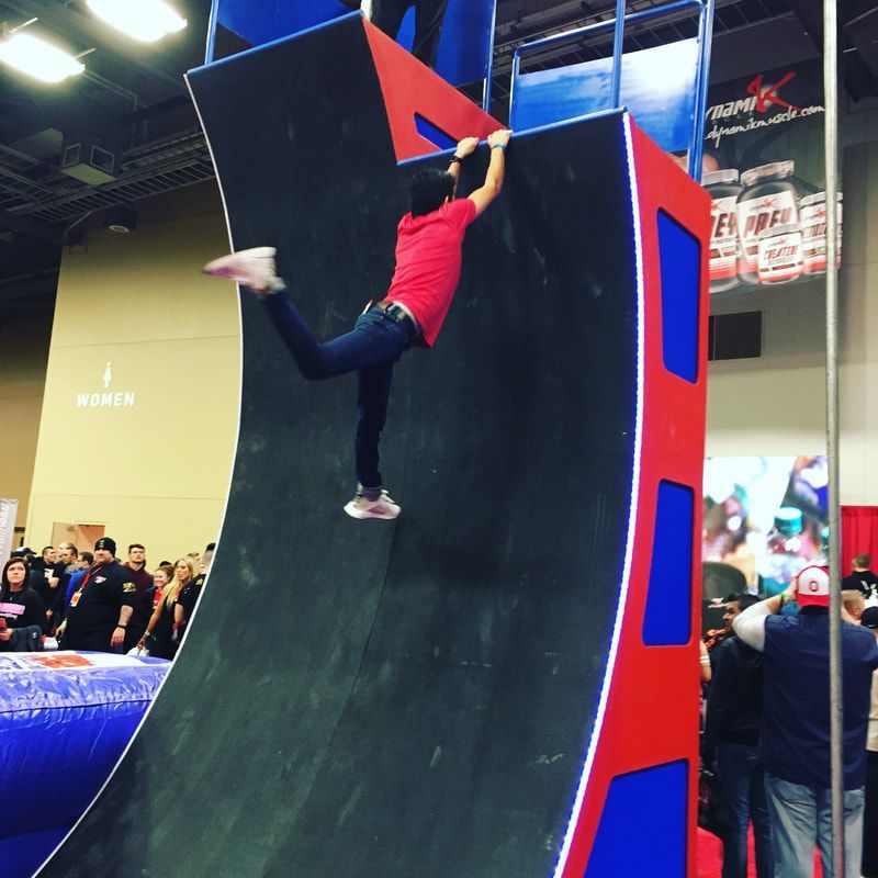 A woman in a red shirt is climbing a wall