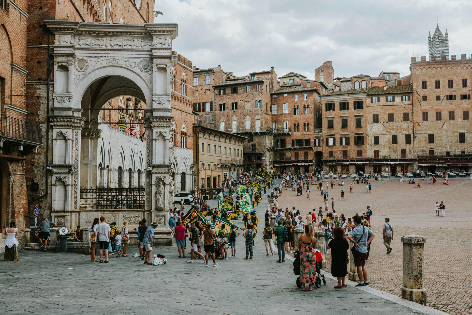 A group of people are standing in a square in front of a building.