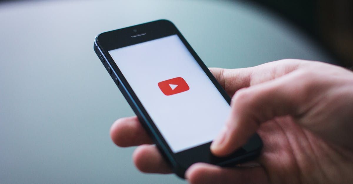 A person is holding a cell phone with a youtube logo on the screen.