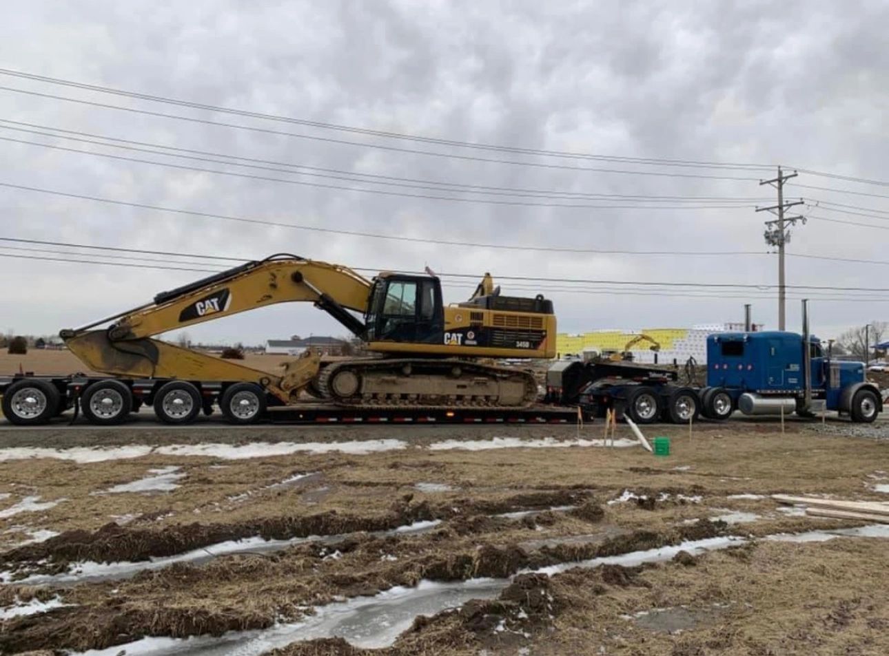 A large yellow excavator is being transported on a trailer.