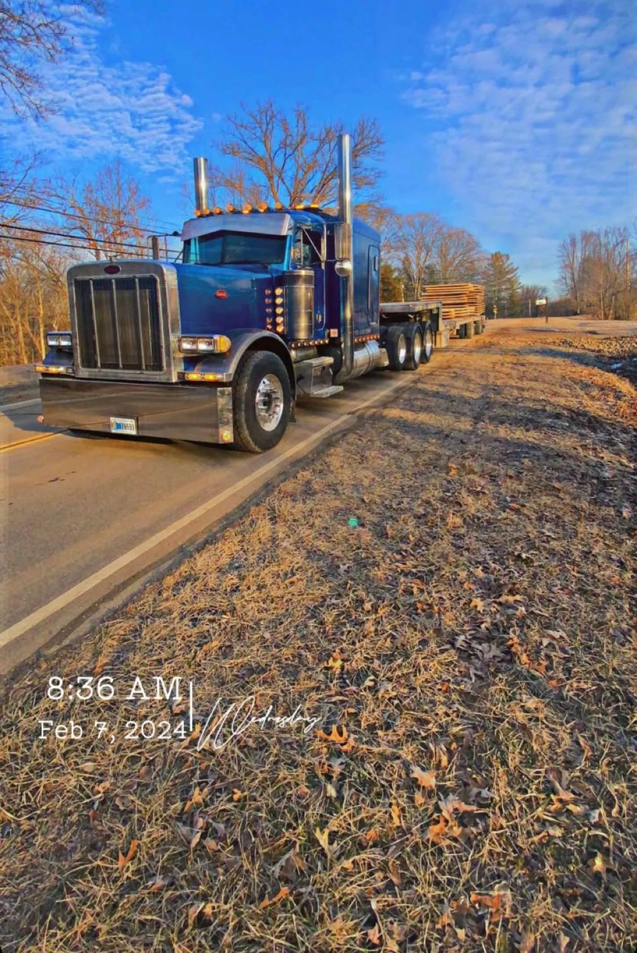 A blue semi truck is parked on the side of the road.