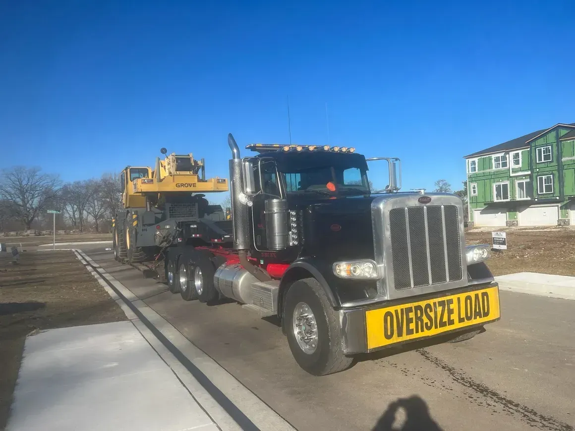 A large semi truck is driving down a road with a yellow sign on the front that says `` oversized load ''.